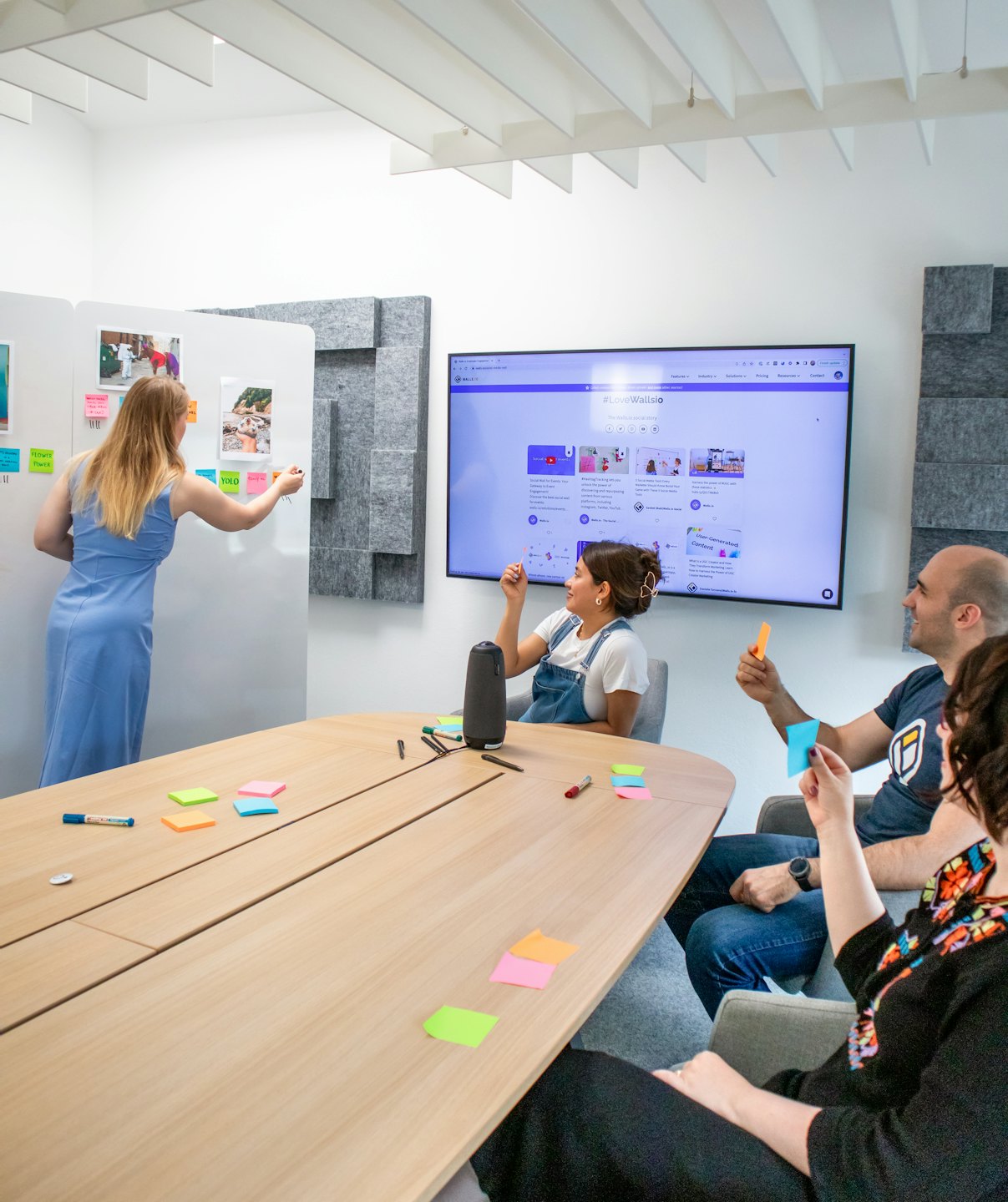Equipo diverso haciendo una lluvia de ideas frente a un monitor y notas adhesivas.